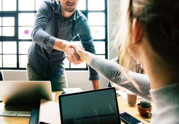 man shaking hands with woman in business meeting